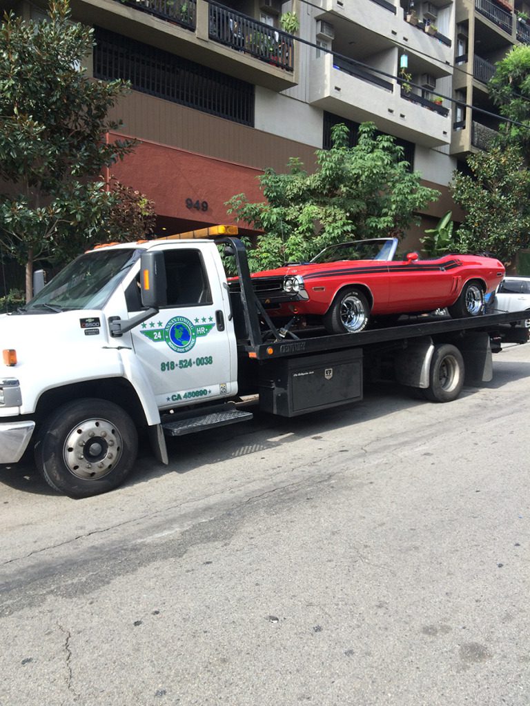 Car-Towing-In-Los-Angeles-–-What-You-Need-To-Know A tow truck towing a red car on the road.