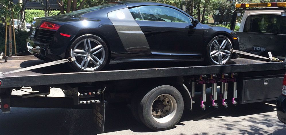 How-Do-I-Get-Cheap-Towing-in-Hollywood-CA-1 A black car is being towed by a tow truck.