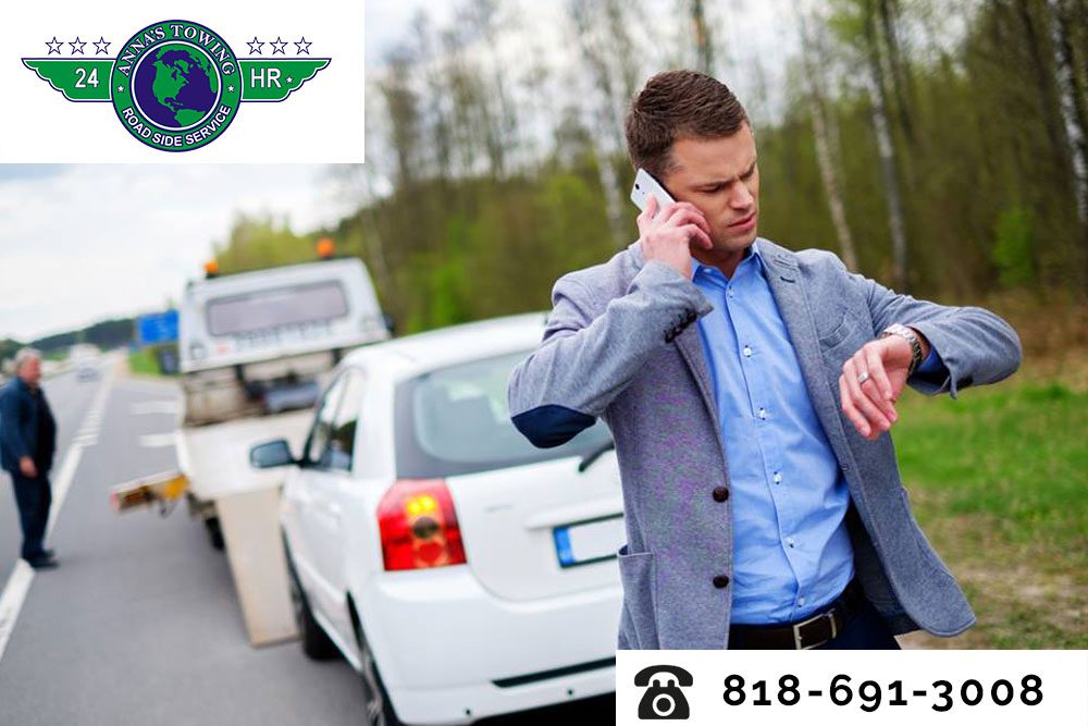 Stay-Safe-Thanks-to-Santa-Clara-Towing A man on the side of the road talking to someone on his phone.