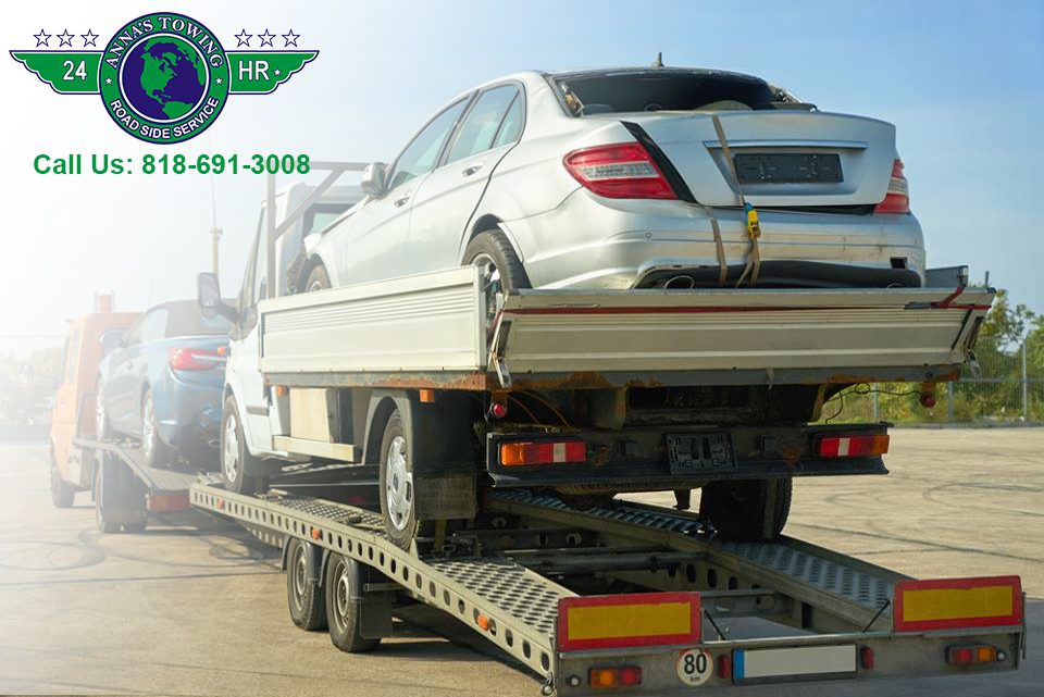 Towing-Drivers-Have-to-Face Tow truck transporting two silver cars.