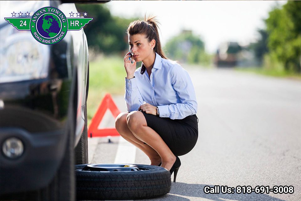 Van-Nuys-Towing-Will-Take-Care-of-Your-Car-While-You-Travel- Woman calling for roadside assistance with flat tire.