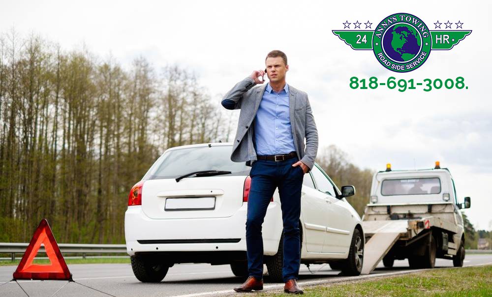 When-You-Need-Emergency-Valley-Village-Towing A man standing on the side of a road talking on his phone.