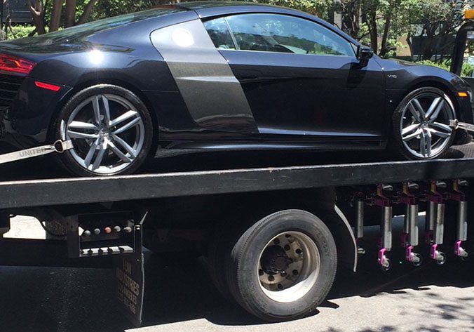 How-Do-I-Get-Cheap-Towing-in-Hollywood-CA-1 A black car is being towed by a tow truck.