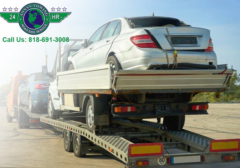 Towing-Drivers-Have-to-Face Tow truck transporting two silver cars.