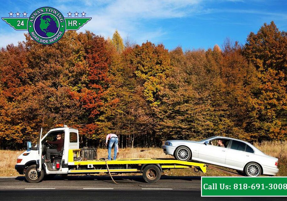 Valley-Village-Towing-Tips-On-How-To-Call-Roadside-Assistance-When-It’s-Raining A tow truck towing a white car on the side of a road.