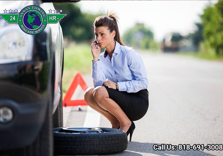 Van-Nuys-Towing-Will-Take-Care-of-Your-Car-While-You-Travel- Woman calling for roadside assistance with flat tire.